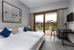 two beds in a room with a desk and a desk at Amarin Seminyak in Seminyak