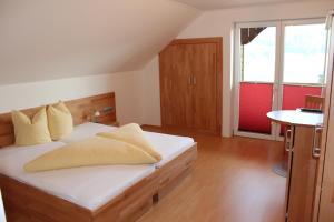 a bedroom with a bed with white sheets and yellow pillows at Haus Kalt in Weissensee