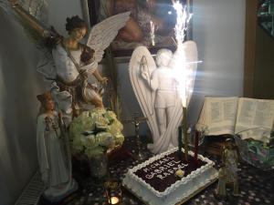 una mesa con un pastel y estatuillas de ángel y una vela en St Michael, en Međugorje