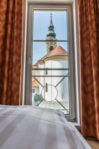
a window with a view of a building with a clock on it at Familie Hopfeld - Hotel Dreikönigshof in Stockerau
