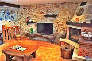 a living room with a stone fireplace and a television at Casa Combarro in Combarro