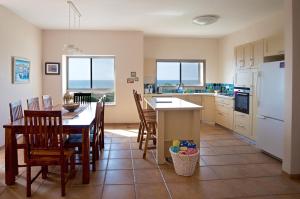 eine Küche mit einem Tisch und Stühlen sowie einem weißen Kühlschrank in der Unterkunft Nahariya Beachfront in Naharija
