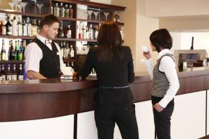 a man and two women standing at a bar at Hotel Activa in Muszyna