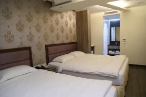 two beds in a hotel room with white sheets at 德瑞旅店Direct Hotel in Kaohsiung