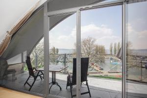 einen Balkon mit einem Tisch und Stühlen sowie einem großen Fenster in der Unterkunft Hotel Seehof in Uhldingen-Mühlhofen