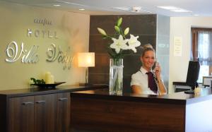 a woman talking on a cell phone at a hotel lobby at Hotel Villa Völgy Wellness & Konferencia in Eger