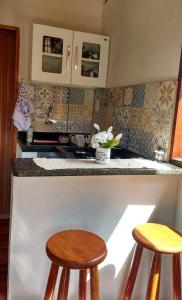 una cocina con 2 taburetes de madera en un mostrador en Chalé Primavera 1, en São Thomé das Letras