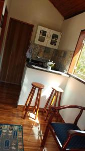 a kitchen with two stools and a counter top at Chalé Primavera - Eubiose in São Thomé das Letras