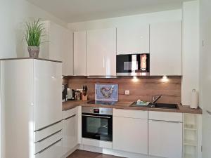 a white kitchen with white cabinets and a sink at Michels Kate in Heiligenhafen