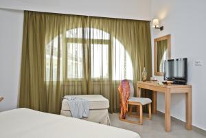 um quarto com uma cama, uma secretária e uma televisão em Xenia Hotel em Naxos Chora