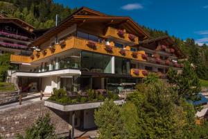 a house in the mountains with a balcony at Hotel Garnì Gardena - Appartments in Santa Cristina Gherdëina
