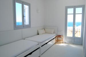 Cette chambre blanche dispose d'un canapé et de deux fenêtres. dans l'établissement Ios art villa, à Ios Chora