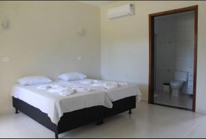 a bedroom with a bed and a bathroom with a toilet at Pousada Caminho das Ilhas in Pontal do Paraná