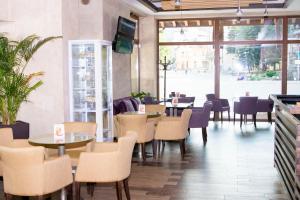 a restaurant with tables and chairs and a large window at Hotel Etropolia in Etropole