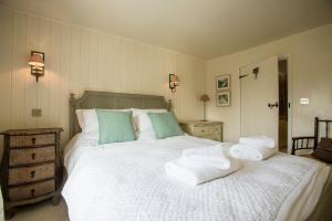 a bedroom with a large white bed with towels on it at Nutshell in Aldeburgh