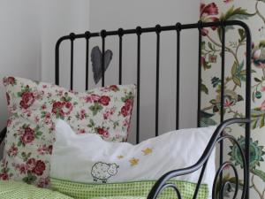- un lit bébé avec des oreillers à motifs floraux et un rail noir dans l'établissement Gästehaus 26/2, à Bad Urach