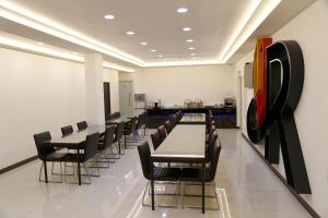 a dining room with black chairs and tables and a white wall at 德瑞旅店Direct Hotel in Kaohsiung