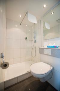 a white bathroom with a shower and a toilet at Hotel Restaurant Neuhaus in Nussbaumen