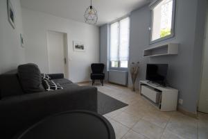 a living room with a couch and a tv at La Petite Madame in Moret-sur-Loing