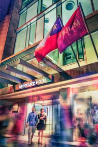 a man and woman walking in front of a mercure hotel at Mercure Santiago Centro in Santiago