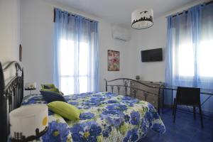 a bedroom with a bed and a table and windows at Liberty Guest House in Alghero