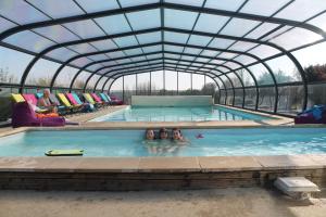 a couple of people in a swimming pool with a greenhouse at Emerald Coast Gites and Lodge in Hénansal