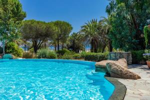 a swimming pool with a rock in a yard with trees at Résidence Paese Serenu in Porto-Vecchio