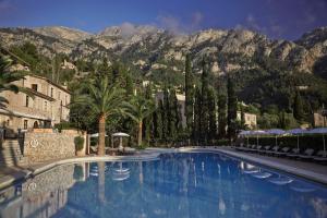 德亞的住宿－La Residencia, A Belmond Hotel, Mallorca，一座棕榈树和山脉的大型游泳池