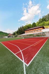 a red tennis court with a building in the background at B&B Zlatna Nit in Bosanska Krupa