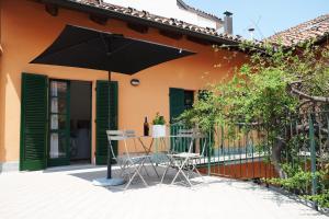 un patio con tavolo, sedie e ombrellone di La Casa di Ringhiera ad Alba