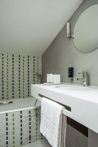 La salle de bains est pourvue d'un lavabo blanc et d'un miroir. dans l'établissement Hôtel de la Place du Louvre - Esprit de France, à Paris