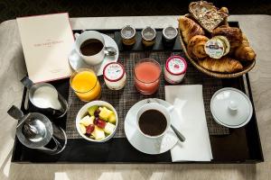 a tray with cups of coffee and a basket of bread at Hôtel Parc Saint-Séverin - Esprit de France in Paris