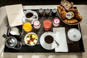 uma bandeja com chávenas de café e uma cesta de pão em Hôtel Parc Saint-Séverin - Esprit de France em Paris