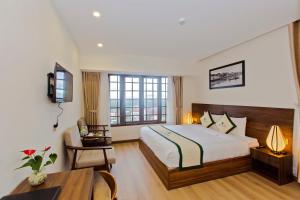 a hotel room with a bed and a table and a desk at Ally Beach Boutique Hotel Hoian in Hoi An