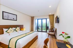 a bedroom with a large bed and a table at Ally Beach Boutique Hotel Hoian in Hoi An +55 photos