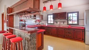 eine große Küche mit Holzschränken und roten Arbeitsplatten in der Unterkunft Villa la senda del majorero in Antigua