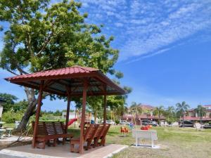 a gazebo with two benches in a park at Shuang Yang Sekinchan Homestay 7 in Sekincan