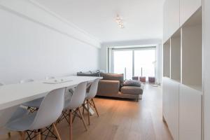 a white kitchen with a table and chairs and a couch at Sea View Apartment Knokke in Knokke-Heist