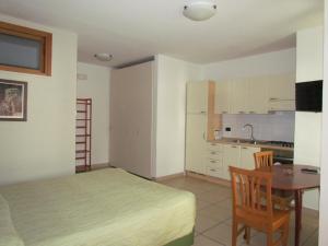 a bedroom with a bed and a table and a kitchen at Miramare Residence in Pozzuoli