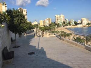 a sidewalk next to a beach with buildings at First line Apartment in Alicante