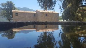 a building is reflected in a pool of water at Maison d'Hôtes Zella in Bains de Guitera