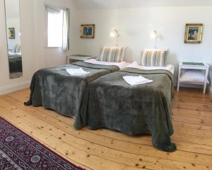 two beds in a room with wooden floors at 27ans Nattlogi in Vadstena