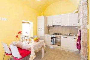 eine Küche mit einem Tisch und Stühlen sowie eine Küche mit weißen Schränken in der Unterkunft Maisonrua' in Ascoli Piceno
