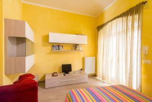 gelbes Zimmer mit einem Bett und einem Schreibtisch mit einem Computer in der Unterkunft Maisonrua' in Ascoli Piceno