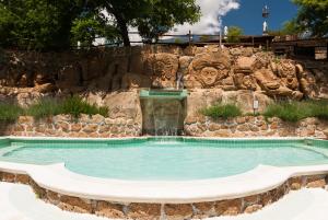 a swimming pool with a water fountain in front of a rock wall at Villaggio Le Querce in Sorano