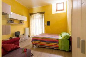 a yellow room with a bed and a couch at Maisonrua' in Ascoli Piceno