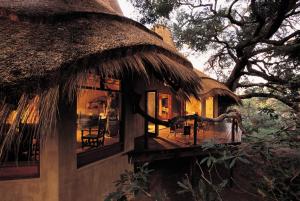 dom z dachem krytym strzechą i tarasem w obiekcie Pondoro Game Lodge w mieście Balule Game Reserve