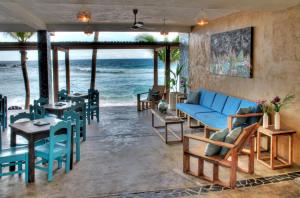 una sala de estar con un sofá azul, mesas y el océano en Casa Bagus en San Agustinillo