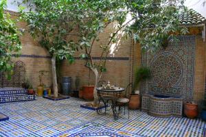 un patio con mesa, árboles y pared en Riad Lalla Fatima, en Fez