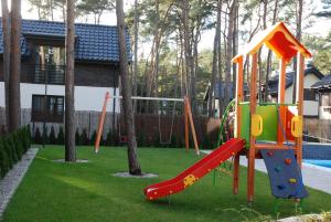 a playground with a slide in a yard at KAMI Ferienwohnungen in Pobierowo